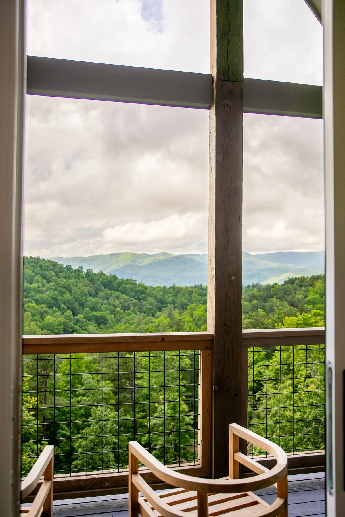 This exterior shot captures a wooden balcony with two chairs poised toward a dramatic mountain view. The setting suggests peaceful mornings with coffee or sunset contemplation, offering guests a private vantage point to enjoy the landscape and quiet moments together.