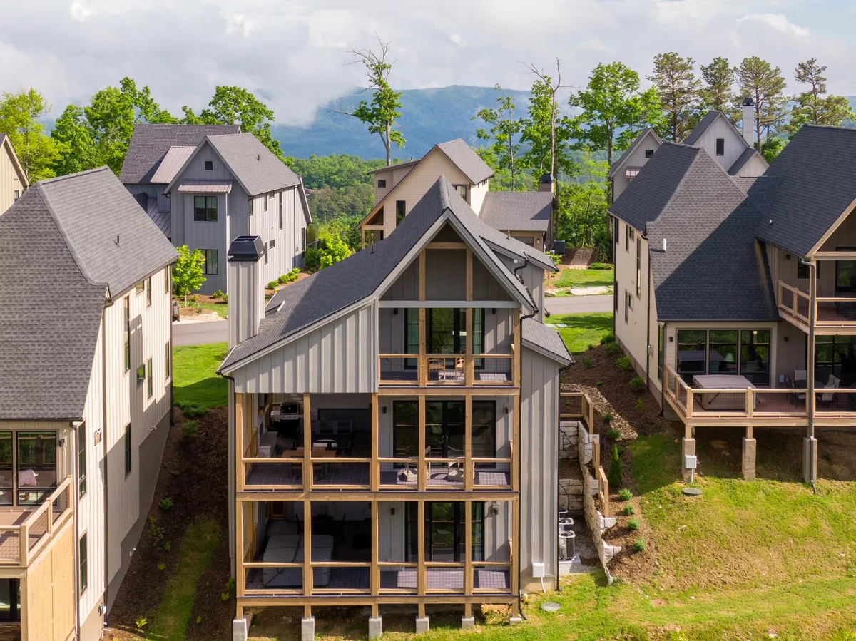 An exterior view of a modern home with large windows, surrounded by lush greenery and set against a stunning mountain backdrop. The image emphasizes the connection between comfortable living spaces and the great outdoors, perfect for relaxing after a day of adventure.