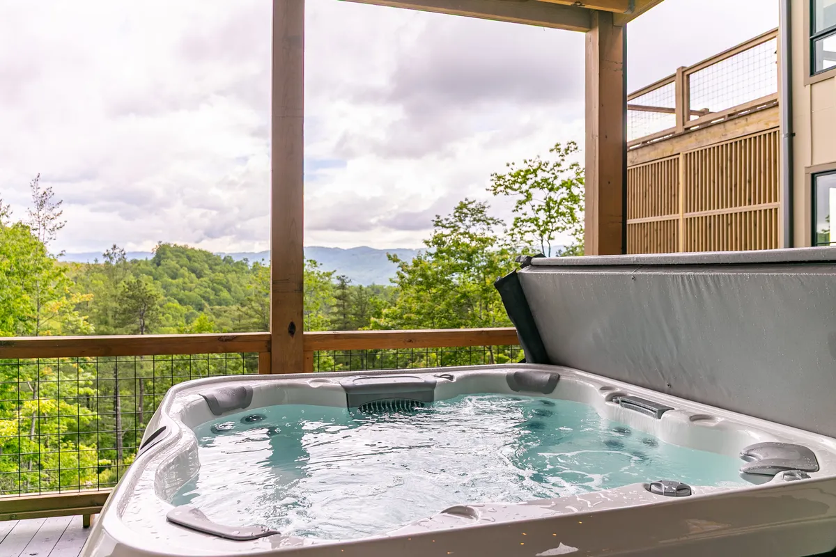This exterior image features a private hot tub with sweeping long-range mountain views, set against a tranquil natural backdrop. The space exudes serenity, ideal for couples to relax and soak under the stars, with the landscape contributing to a sense of intimate seclusion and luxury.